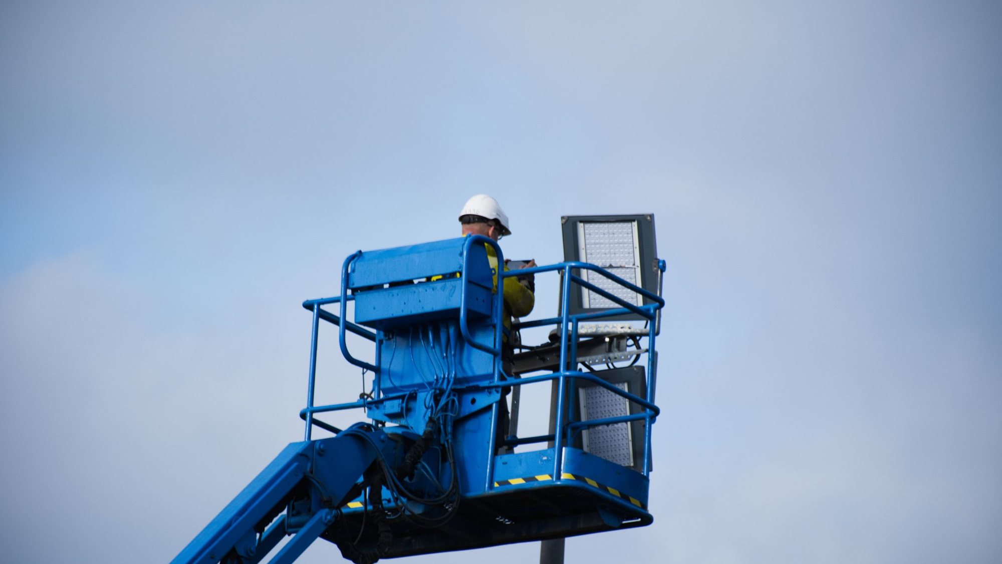 A worker in a hard hat operating a boom lift.